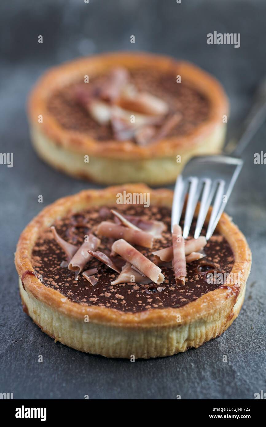 Chocolate marquis tarts with caramel & shaved chocolate garnish on slate - shallow dof Stock Photo