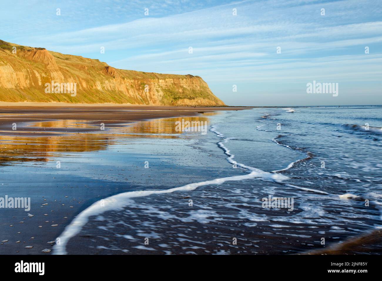 Early morning low tide view of waves flowing across the Cattersty Sands beach at Skinningrove looking towards Hunt Cliff Stock Photo
