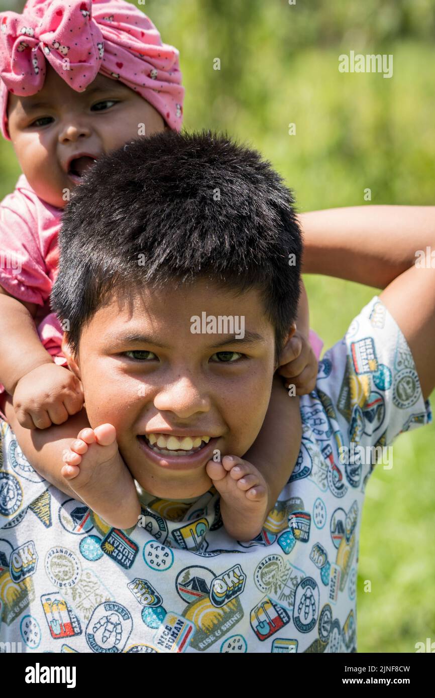 A young Peruvian boy and his baby sister smile in the Peruvian Amazon Stock Photo