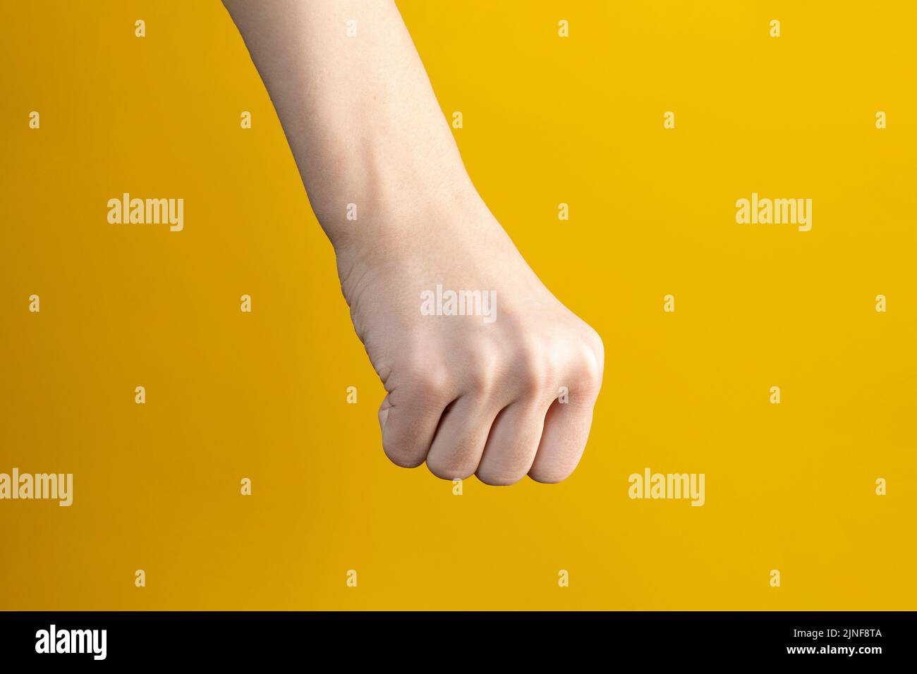 hand with clenched fists against yellow background Stock Photo Alamy