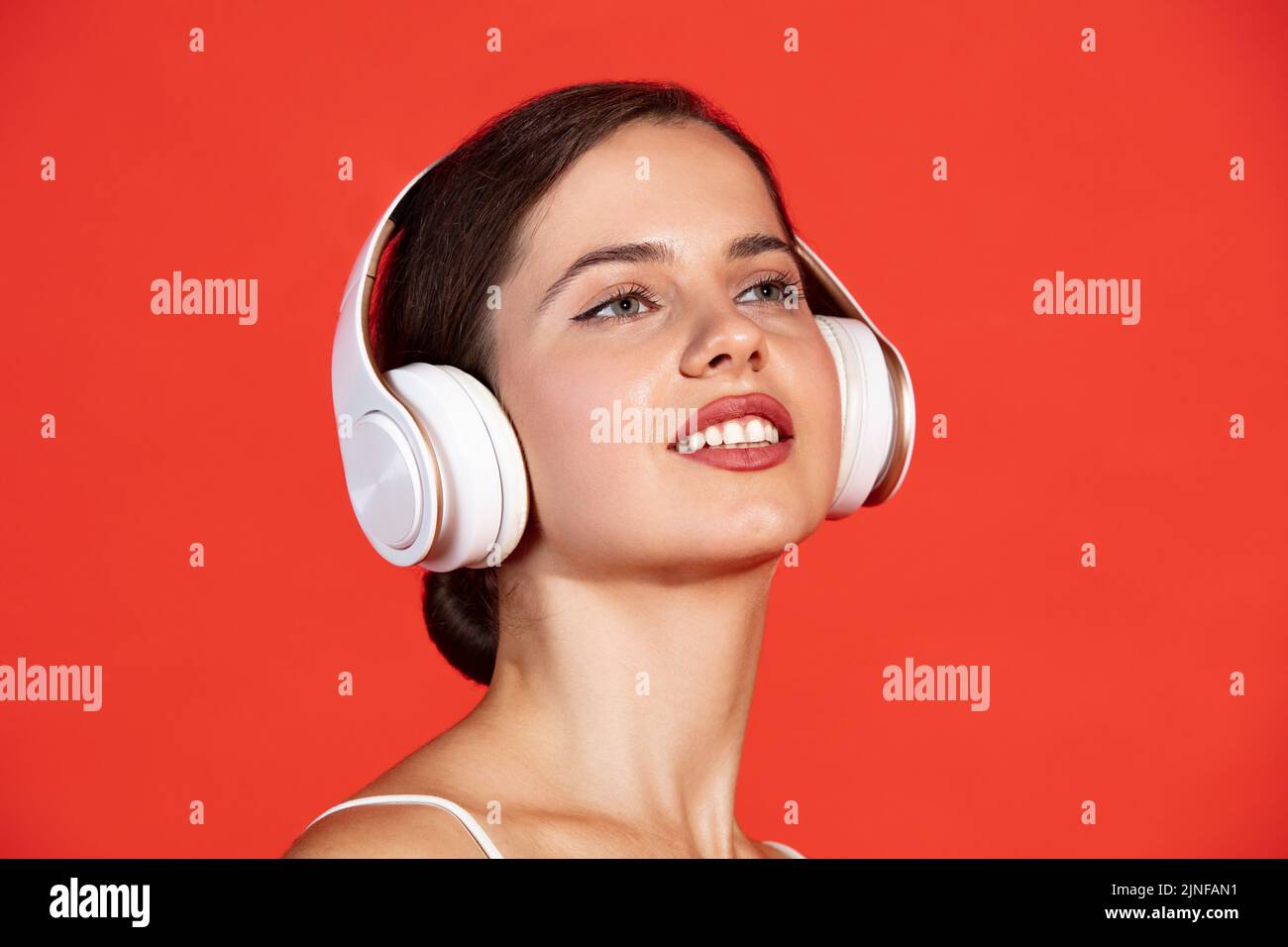 Close-up portrait of beautiful young woman posing in white headphones ...