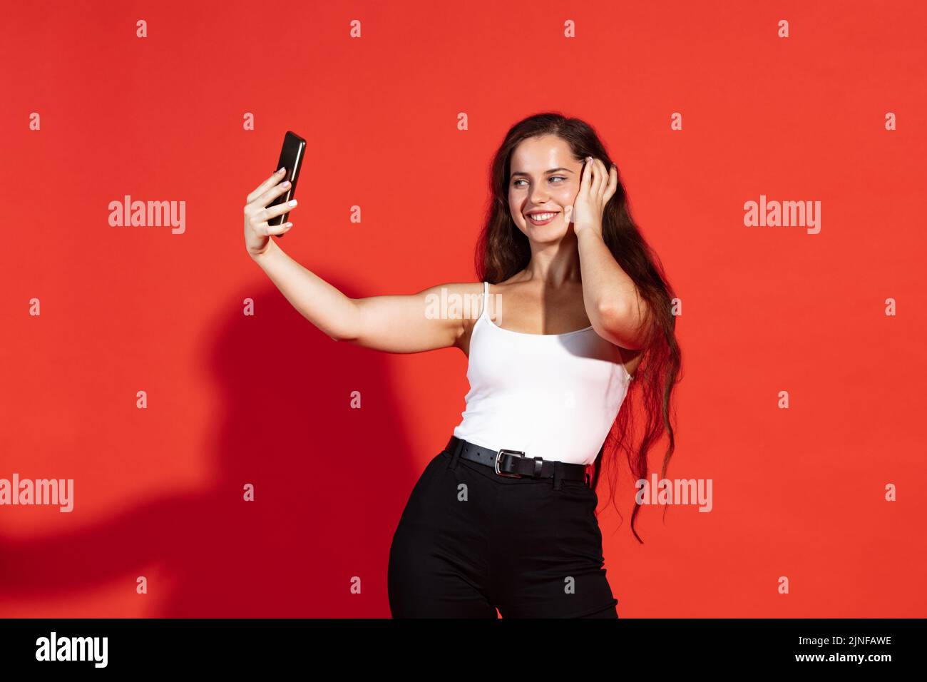 Portrait of beautiful young woman taking selfie with phone isolated ...