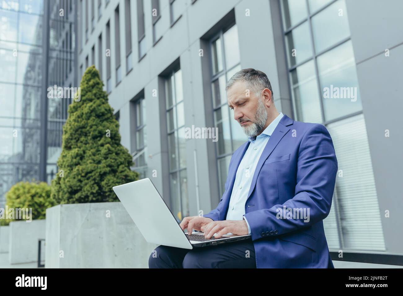 Serious and focused senior gray haired businessman outside office ...