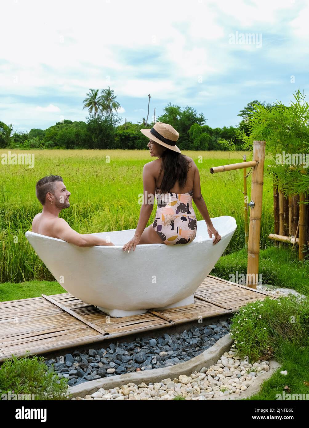 couple men and women in a white bathtub outside looking out over green ...