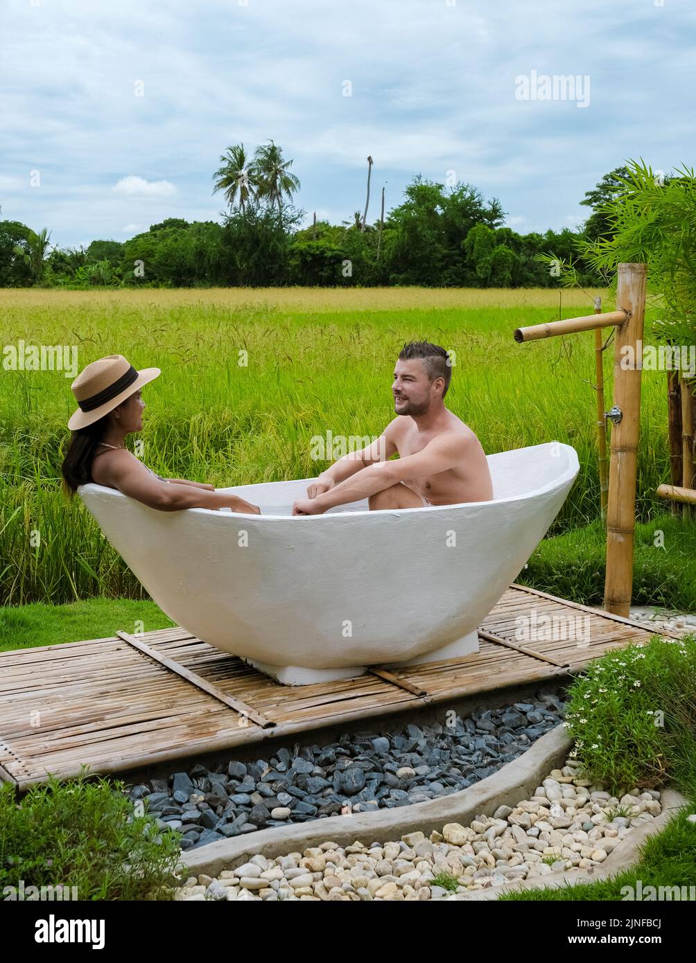 a couple of men and women in a white bathtub outside looking out over a