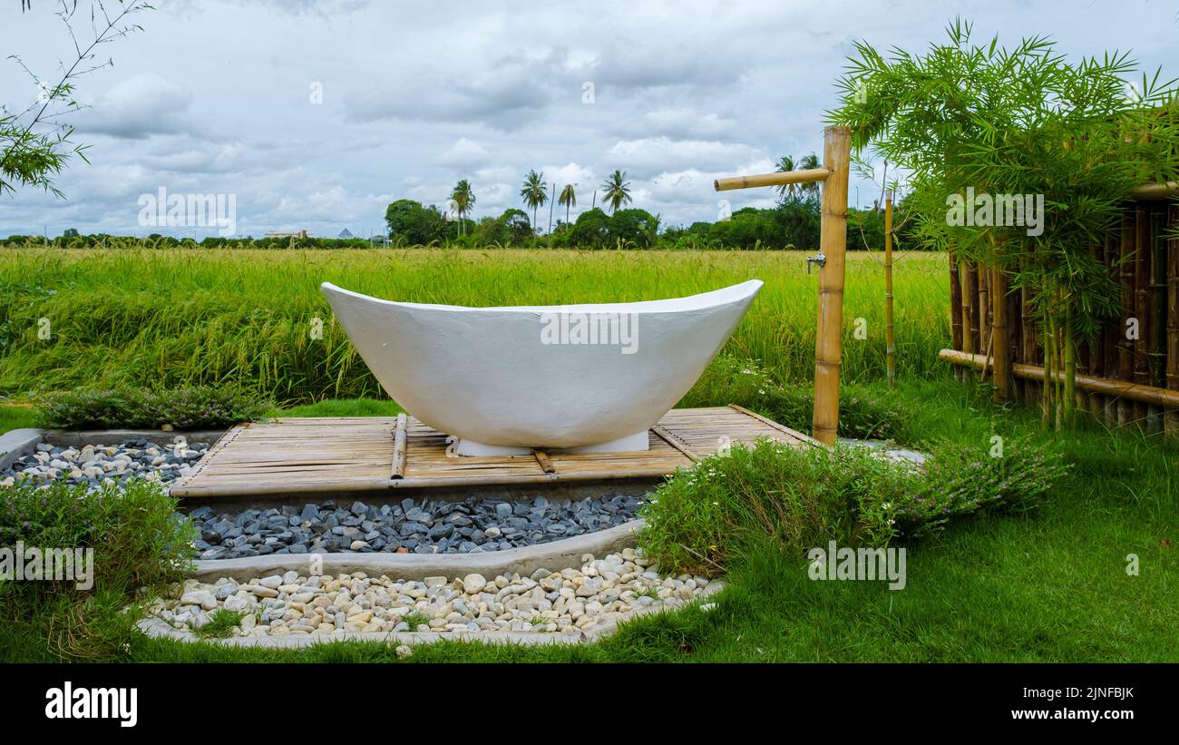 white bathtub outside looking out over a green rice field, bath tub