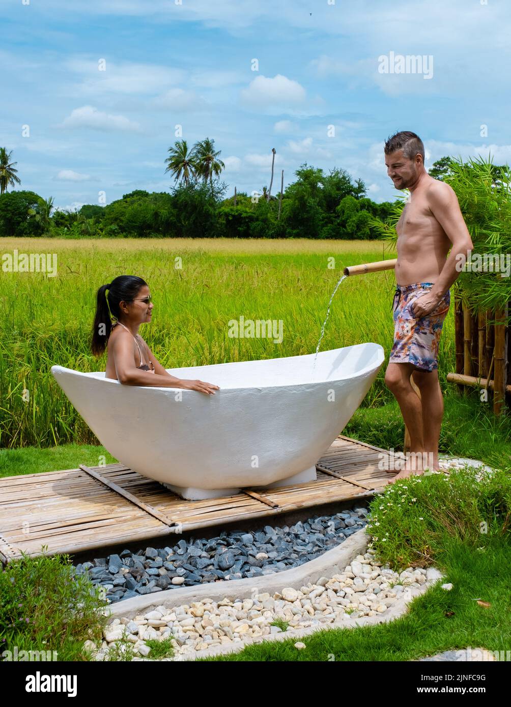 couple men and women in a white bathtub outside looking out over green ...