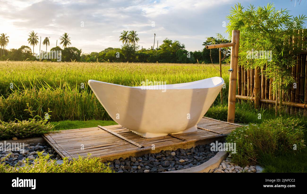 white bathtub outside looking out over a green rice field, bath tub