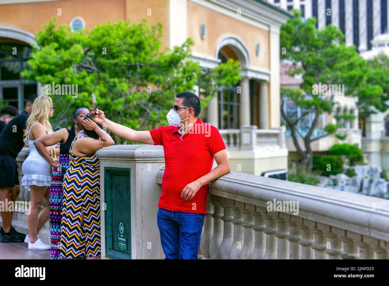 A man wearing a mask is taking a selfie at the Fountains of Bellagio on