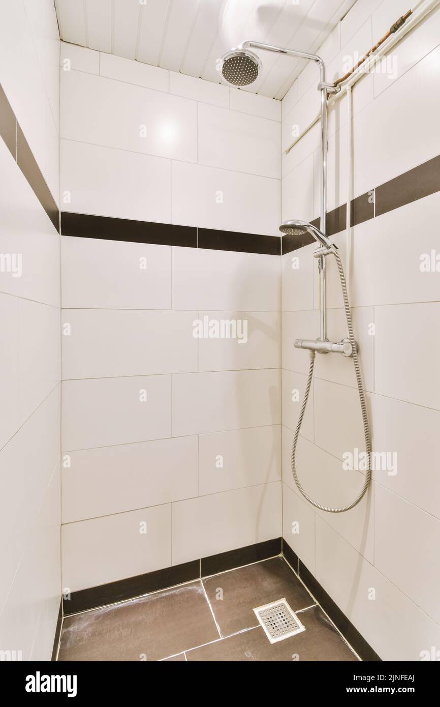 Bathroom with white tiled walls and open shower near sink with toilet