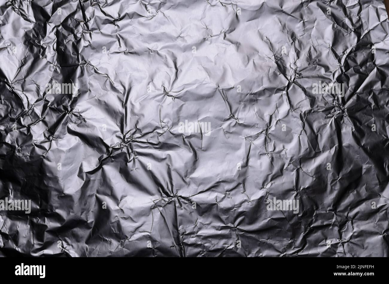 Abstract background of crumpled silver aluminium foil, flat lay view from directly above Stock Photo