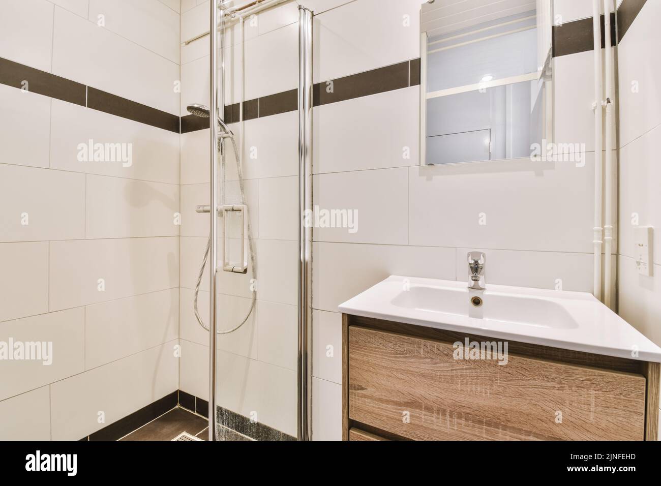 Bathroom with white tiled walls and open shower near sink with toilet