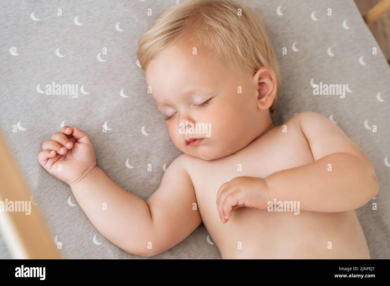 Closeup portrait of adorable baby boy napping in his bed after active play in his bedroom. Childcare concept. Nap time. Safe healthy sleep Stock Photo