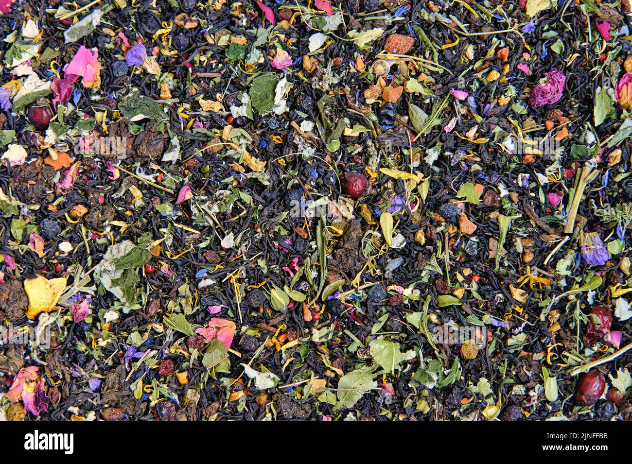 Texture of dry black tea mixed with herbs, leaves and dried berries. Mixed herbal vitamin tea background. Stock Photo