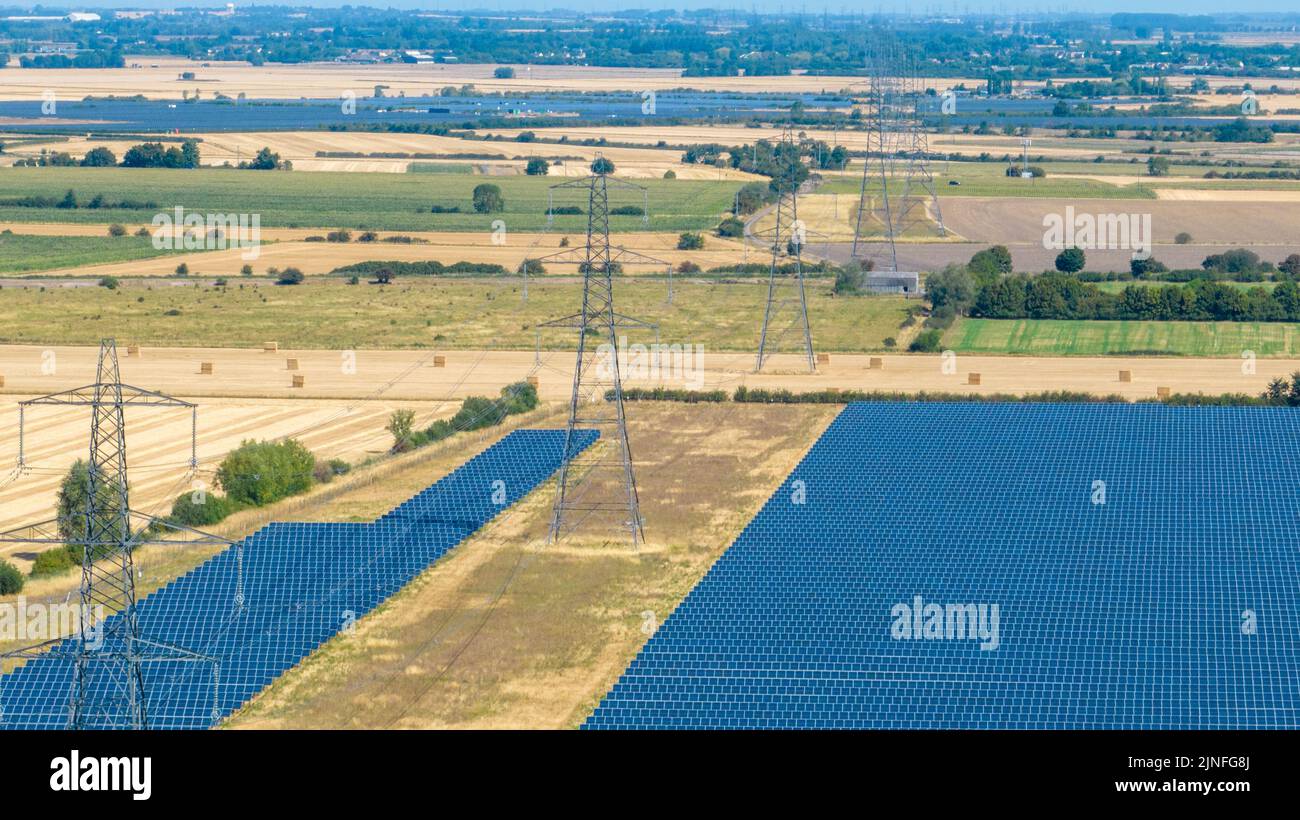 Generic picture dated August 10th shows electricity pylons between a solar power farm in Cambridgeshire as the power crisis goes on with almost a quarter of households already owing £206 with further price increases in the autumn. Stock Photo