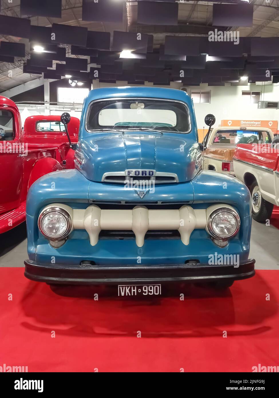 Old blue 1951 Ford F 1 V8 utility pickup truck on a red carpet. Front view. Grille. Exhibit hall. Classic car show. Stock Photo