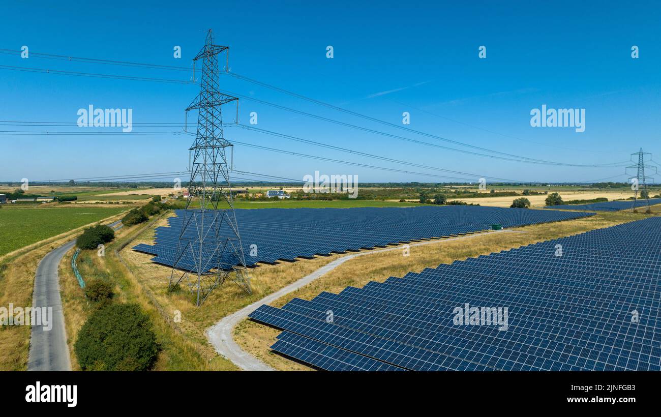 Generic picture dated August 10th shows electricity pylons between a solar power farm in Cambridgeshire as the power crisis goes on with almost a quarter of households already owing £206 with further price increases in the autumn. Stock Photo