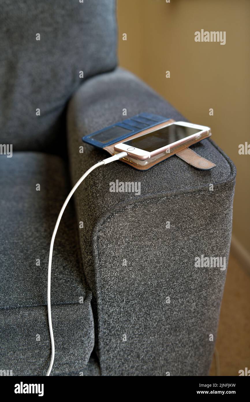 mobile phone charging on arm of lounge chair inside house, hertfordshire england Stock Photo