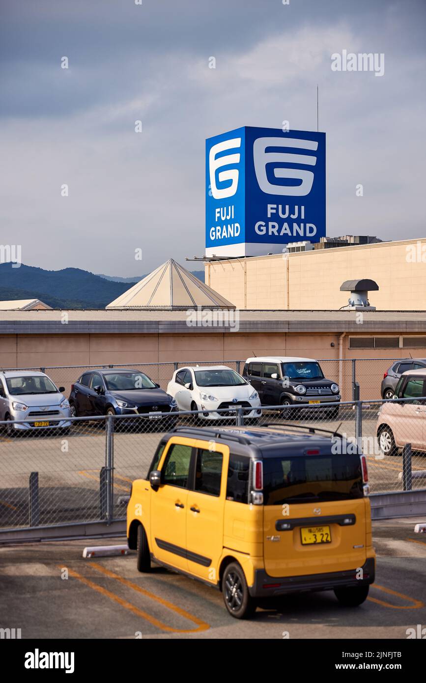 Fuji Grand Kannabe, shopping centre, sign on roof behind parking lot; Fukuyama, Hiroshima Prefecture, Japan Stock Photo