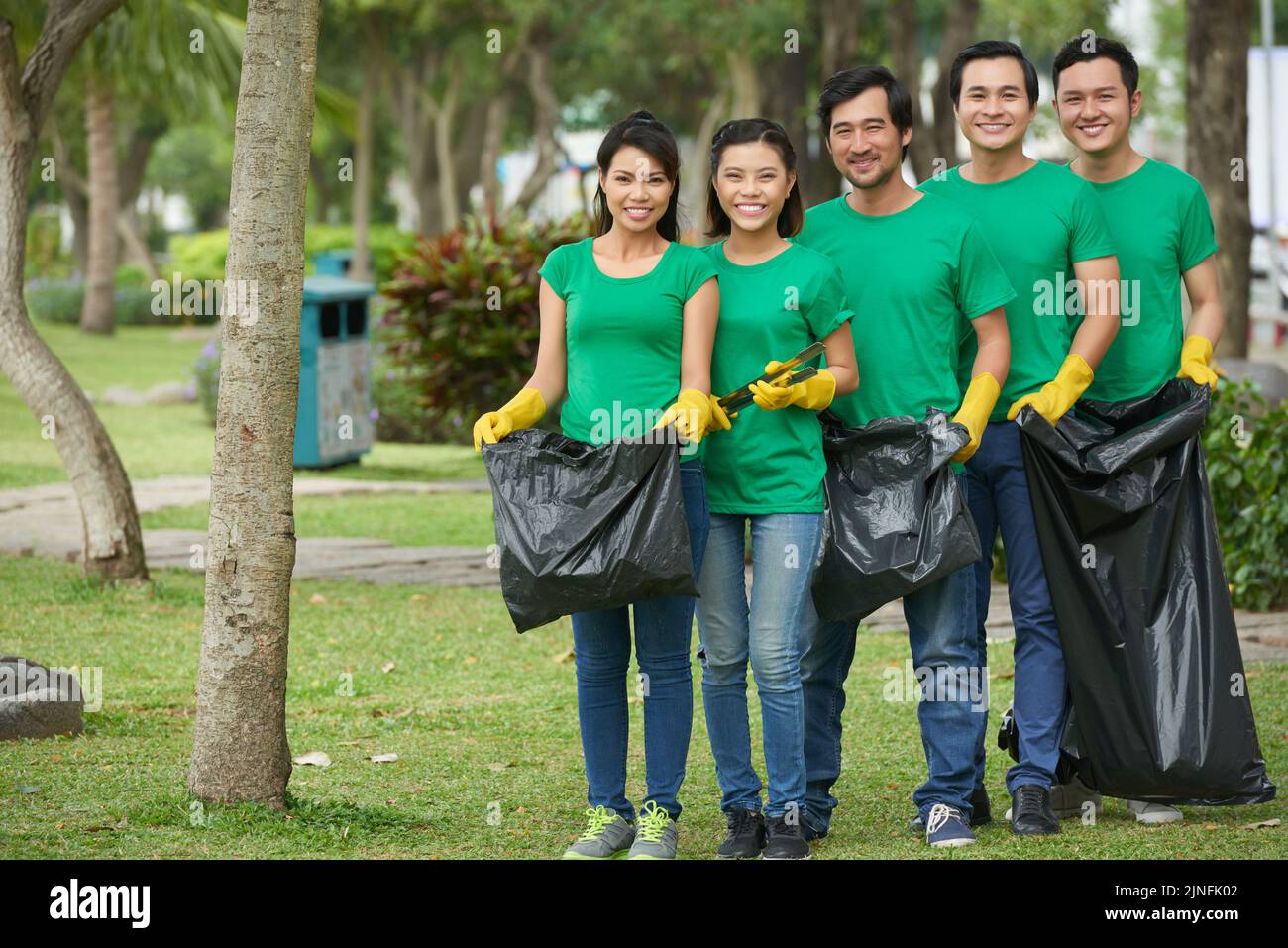 Group of volunteers with big black bin bags collecting litter in park