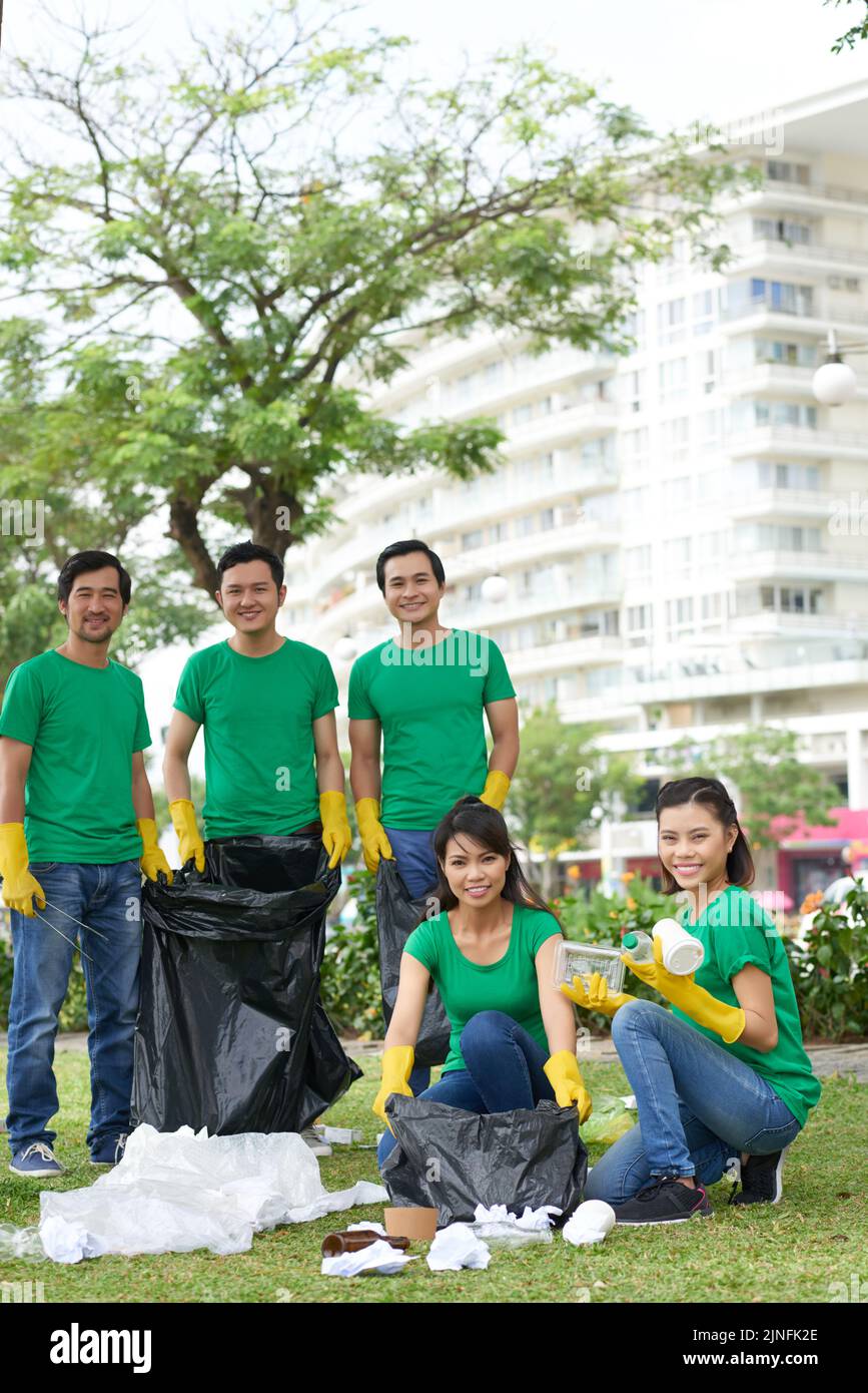 Cheerful green activists picking up litter and putting it in garbage bags Stock Photo