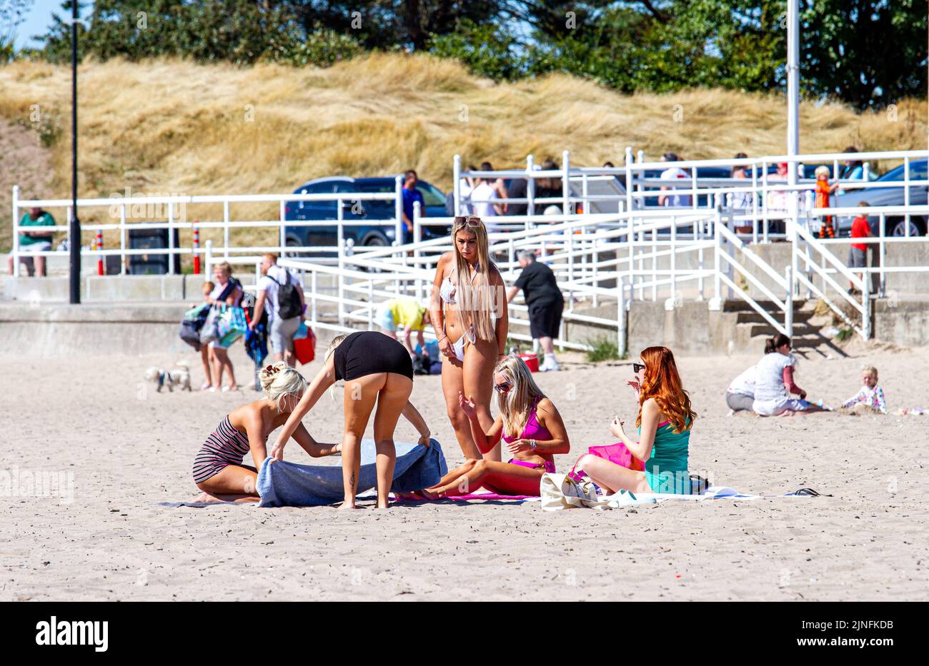 Dundee, Tayside, Scotland, UK. 11th Aug, 2022. UK weather: Extremely hot August temperatures in North East Scotland reached 28°C. Visitors swarm to Broughty Ferry beach in Dundee to enjoy the warm, wonderful summer weather and sunbathe on the sand. Stunning woman enjoying themselves while being photographed sunbathing. Credit: Dundee Photographics/Alamy Live News Stock Photo