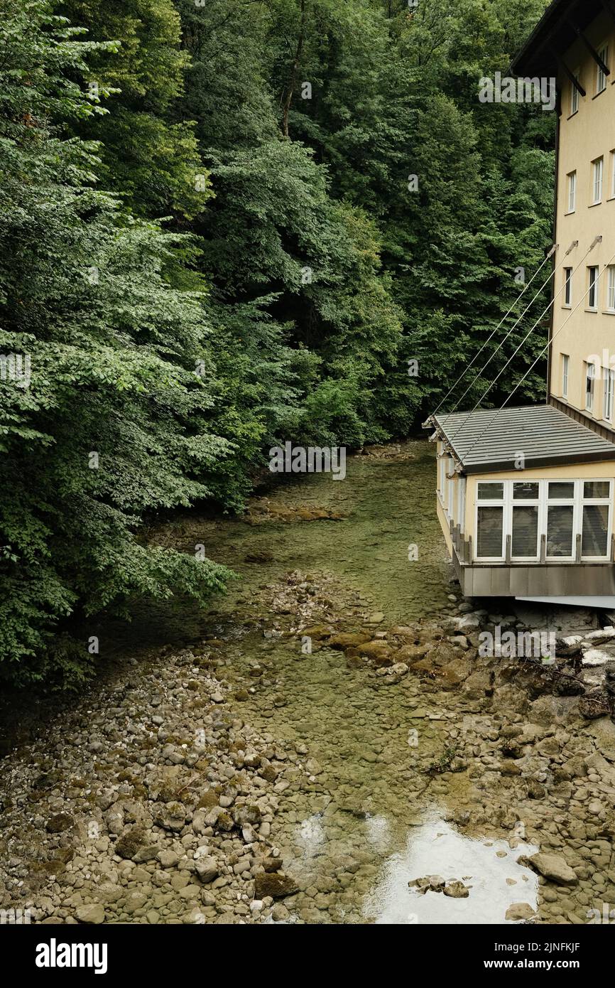 A paper mill surrounded by huge, thick green trees on the Mangfall River in Bavaria, Germany Stock Photo