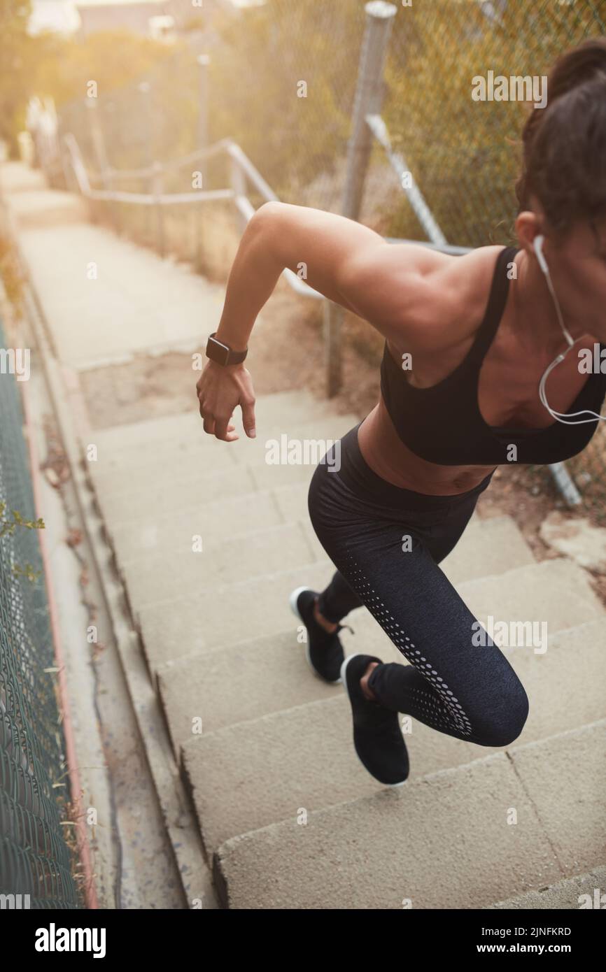 Female athlete running up a staircase in the morning. Sporty young woman having a vigorous training session. Stock Photo