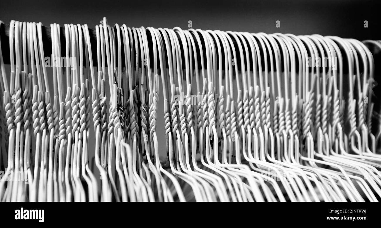 Many several metal wire hangers on pole for hanging clothing in closet storage Stock Photo