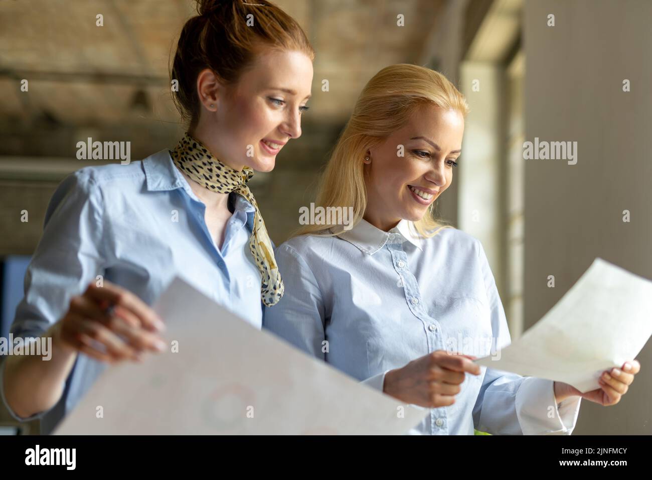 Portrait of two young business people talking about documents in office Stock Photo