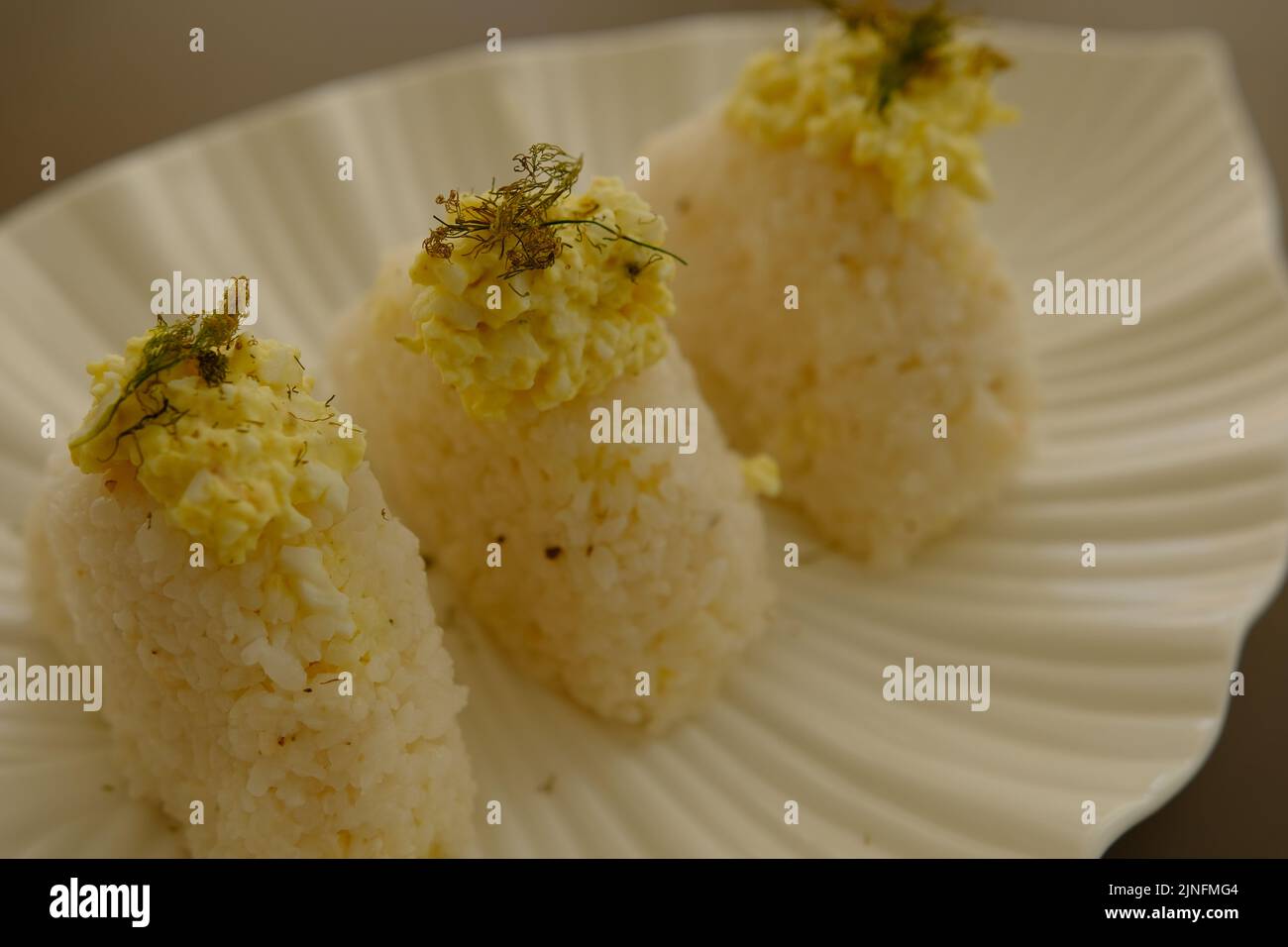 Plate with traditional Japanese onigiri with egg on brown background