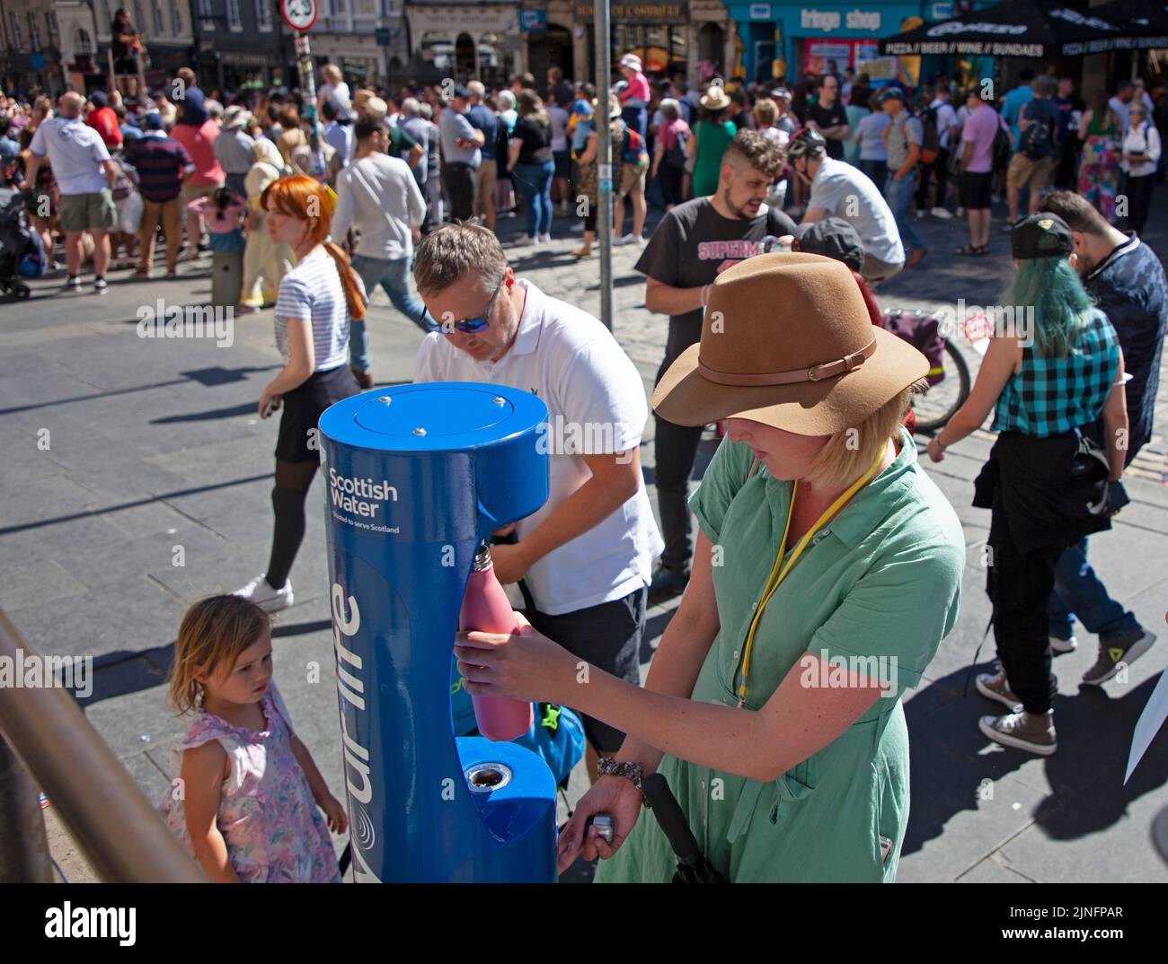 City Centre, Edinburgh, Scotland, UK. 11th August 2022. EdFringe 6th Day on the Royal Mile keeping busy with crowds of people looking for entertainment. Weather 27 degrees centigrade had people looking to top up water bottles and to find shade in the ciy's gardens. Family stop to fill water bottles to assist with rehydration in the very hot weather. Credit: Arch White/alamy live news. Stock Photo