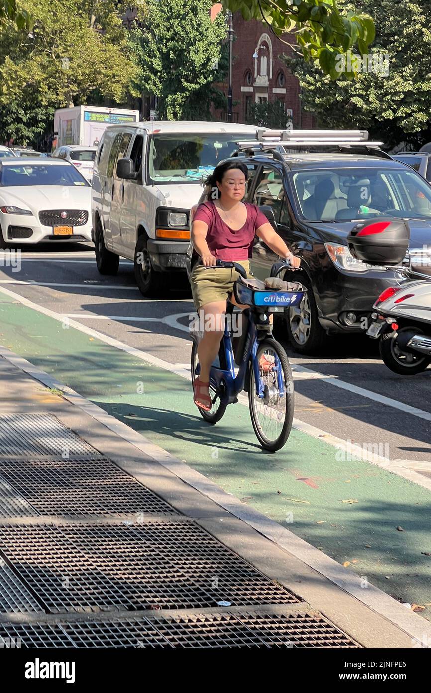 Woman rides a CitiBike along 9th Street in the Park Slope neighborhood of Brooklyn, New York which has bike lanes on many streets. Stock Photo
