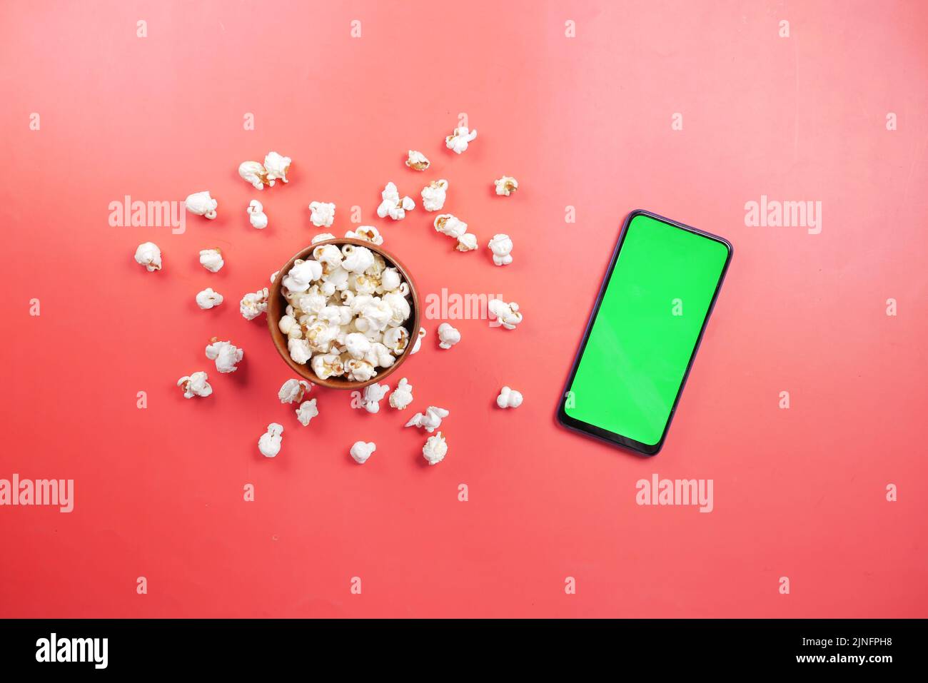 top view of smart phone and popcorn on red background  Stock Photo