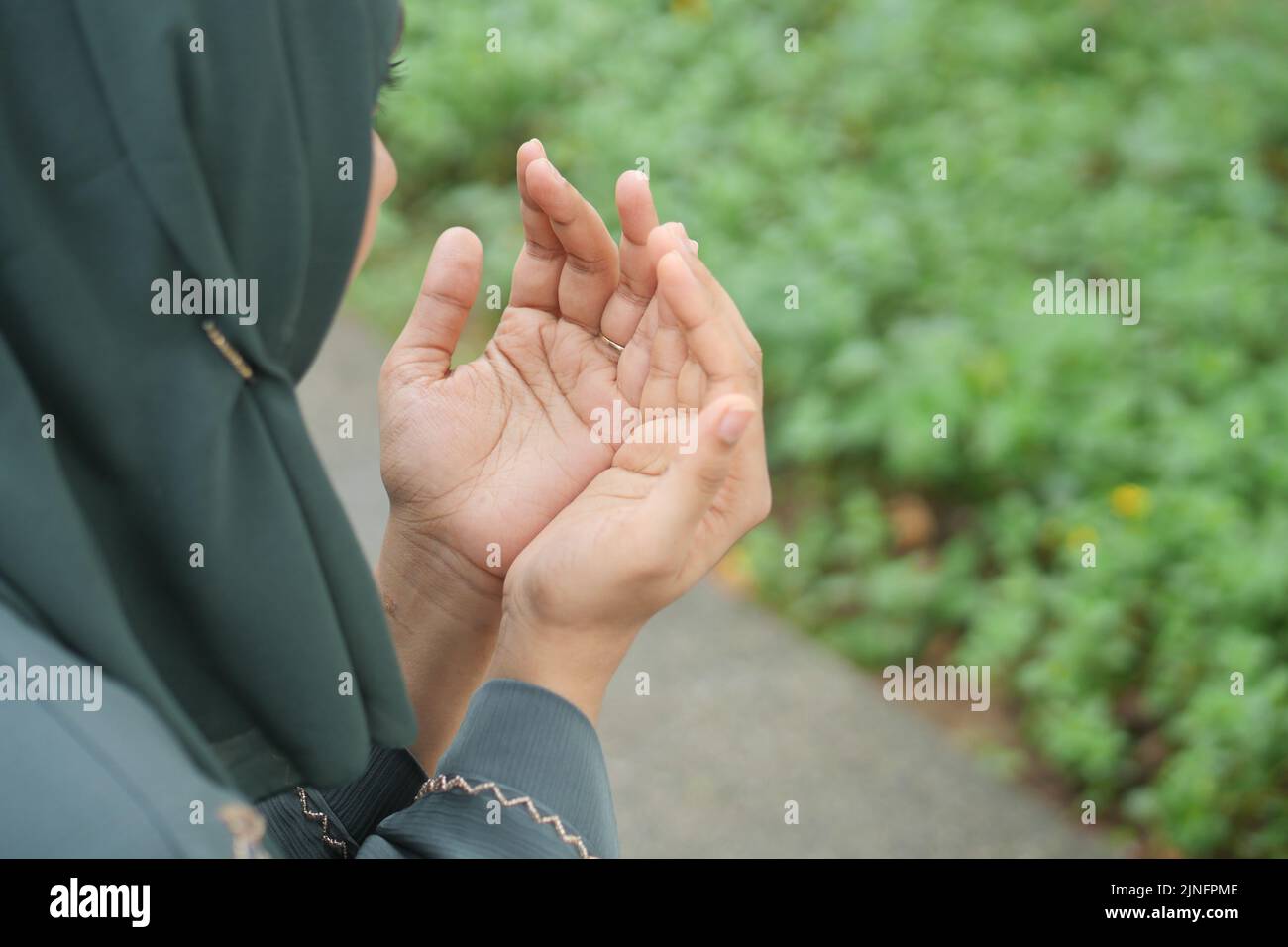rear view of muslim women hand praying at ramadan outdoor  Stock Photo