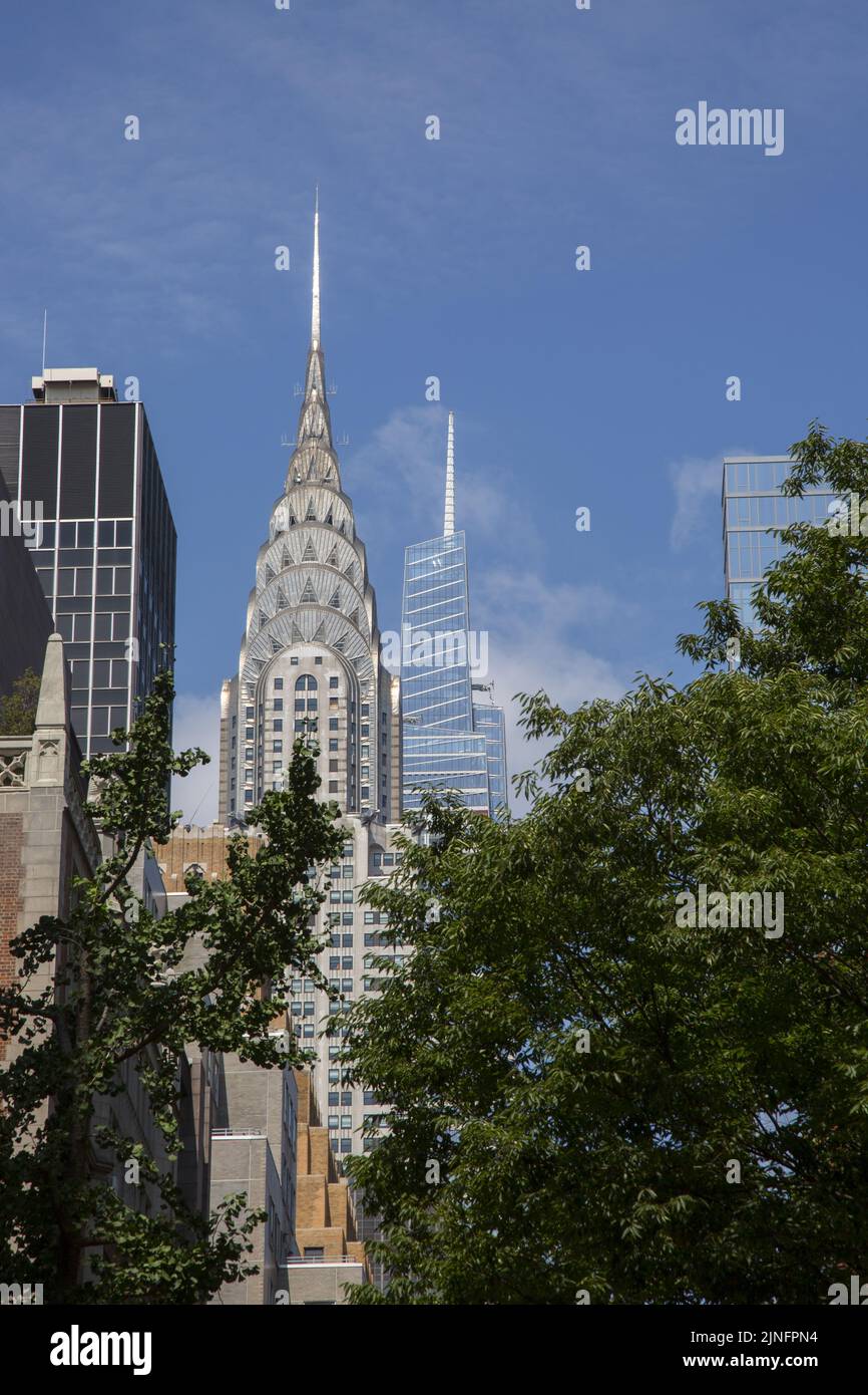 Looking West through the trees from the east end of East 43rd Street  the iconic Chrysler tower with the new 1 Vanderbilt Tower are clearly visible in midtown Manhattan. Stock Photo