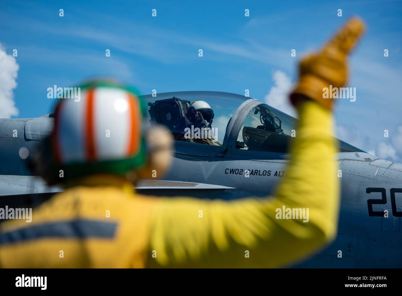 U.S. Navy Shooter Cmdr. Adam Cohen signals ready to launch to a F/A-18E Super Hornet fighter aircraft attached to the Royal Maces of Strike Fighter Squadron 27, on the flight deck of the Nimitz-class aircraft carrier USS Ronald Reagan underway, August 7, 2022 in the Philippine Sea. Stock Photo