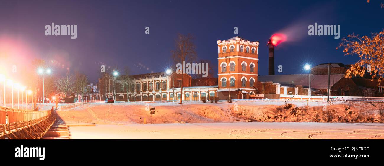 Dobrush, Gomel Region, Belarus.Night Of Old Paper Mill Factory Tower In Winter Season. Night Stars Sky Above Historical Local Landmark Stock Photo