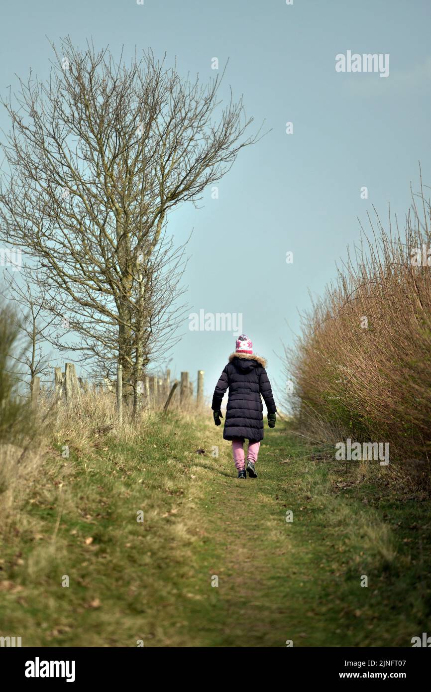lone woman walking on  isolated country track in early spring raydon suffolk england Stock Photo