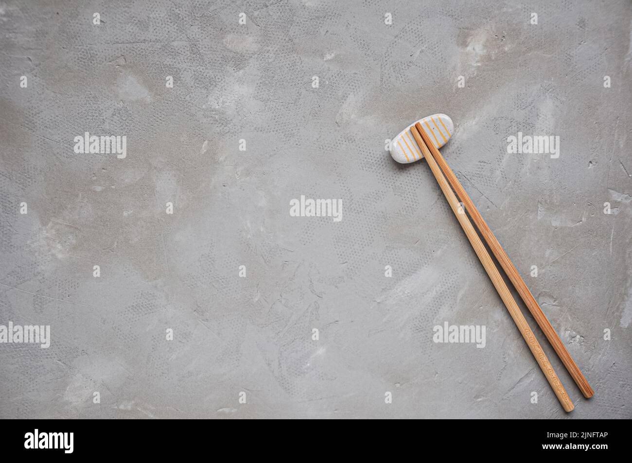 Wooden chopsticks and chopstick rest on a gray background. Top view. Copy space Stock Photo