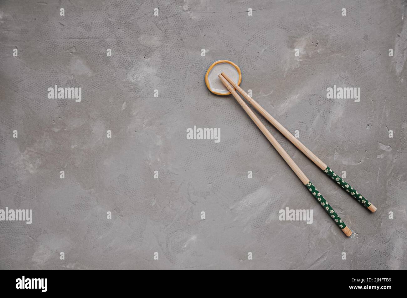 Wooden chopsticks and chopstick rest on a gray background. Top view. Copy space Stock Photo