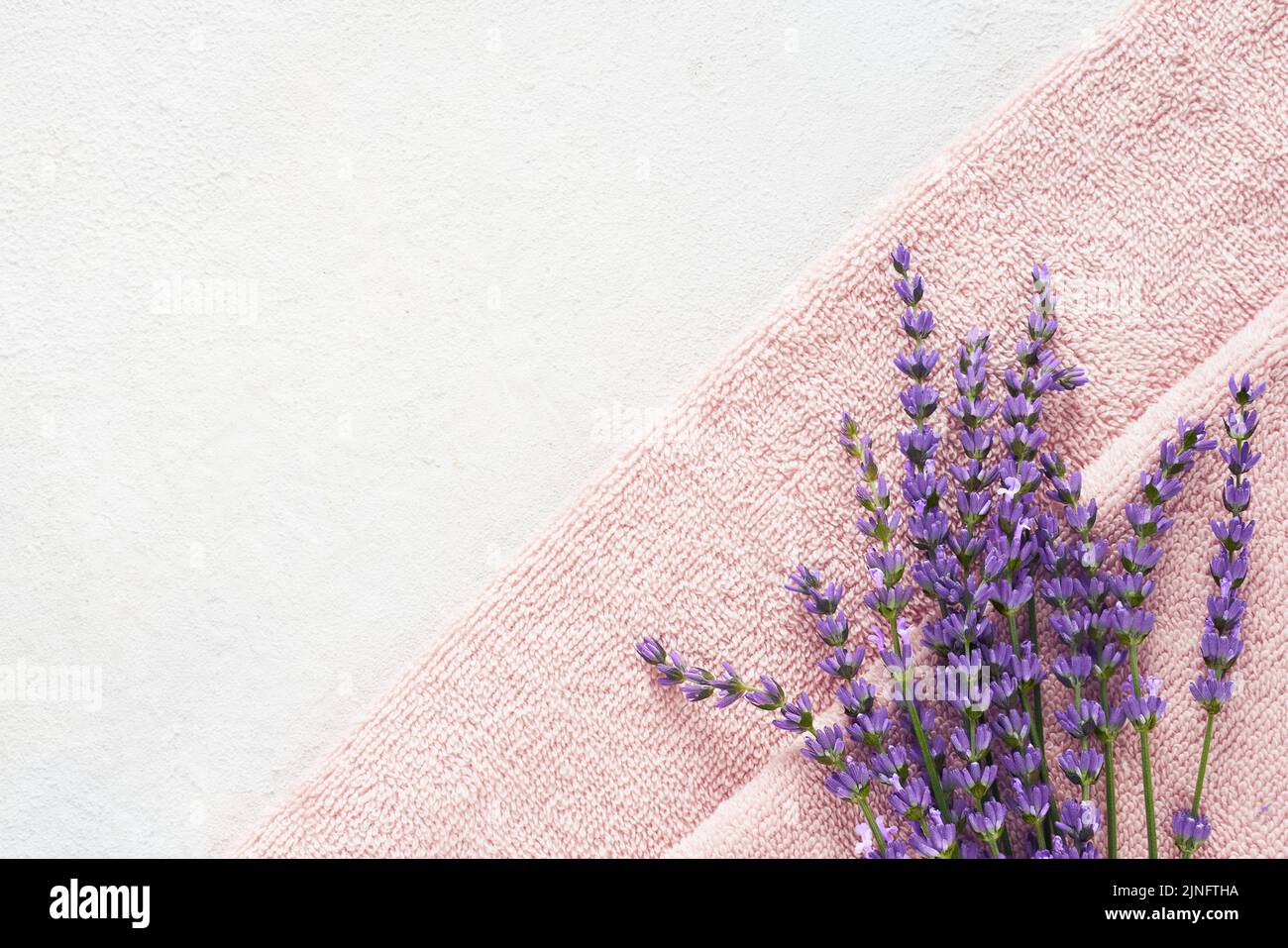 Lavender flowers and pink fluffy towels on the light background. SPA, wellness well-being, body care concept. Copy space for text, top view Stock Photo