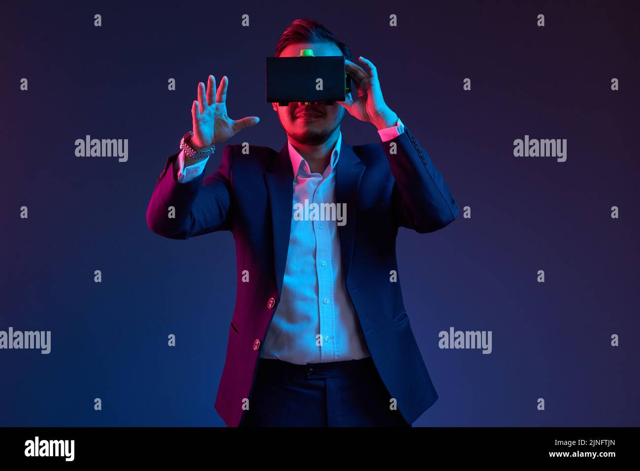 Smiling businessman using virtual reality headset in darkness Stock Photo