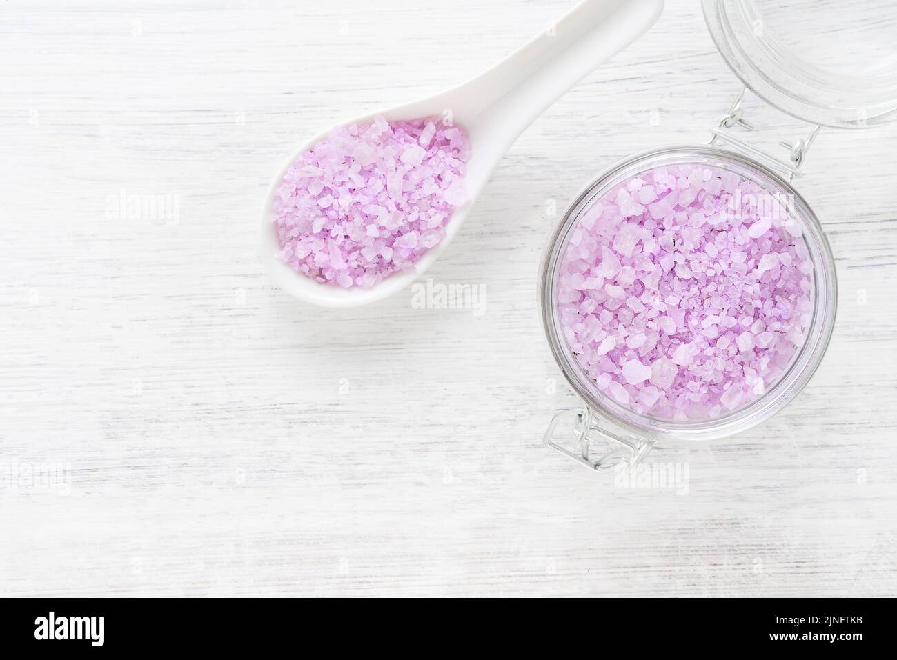 Lilac aroma bath salt in a glass jar on white wooden background. Spa, skincare concept. Top view, copy space. Selective focus Stock Photo