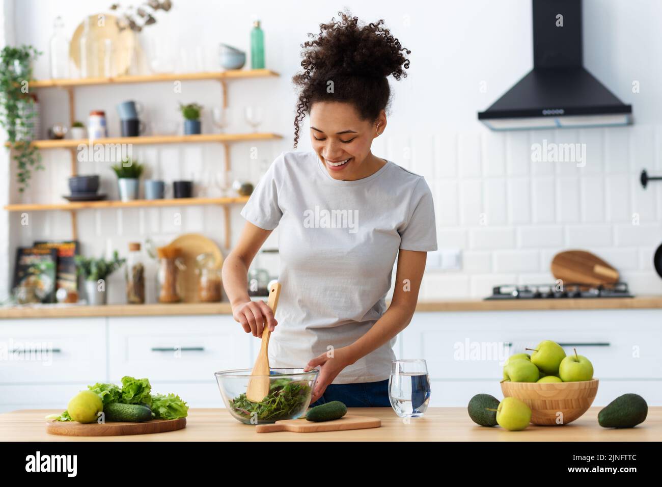 Healthy diet eating African American young female preparing salad in home kitchen Stock Photo