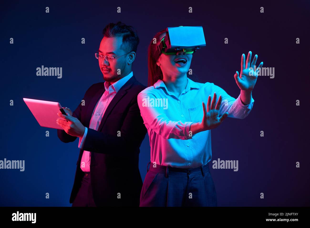 Businessman using app on tablet computer that controls VR headset on young woman Stock Photo