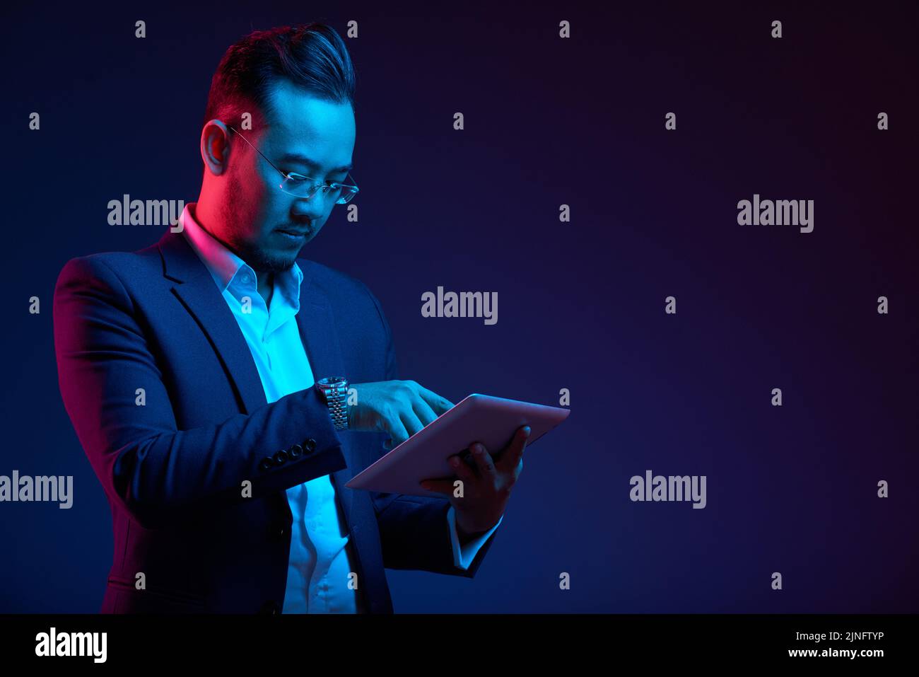 Confident Vietnamese entrepreneur using application in digital tablet Stock Photo
