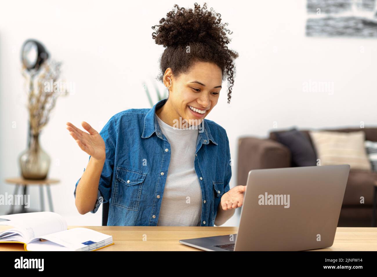 Happy woman young female student using laptop sitting in home having video call learning language Stock Photo
