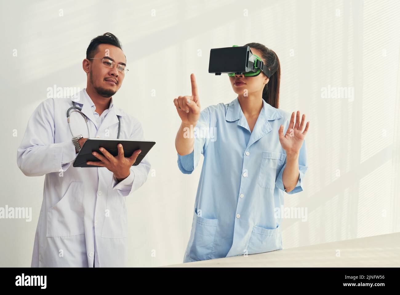 Doctors using application on tablet computer to test VR goggles Stock Photo