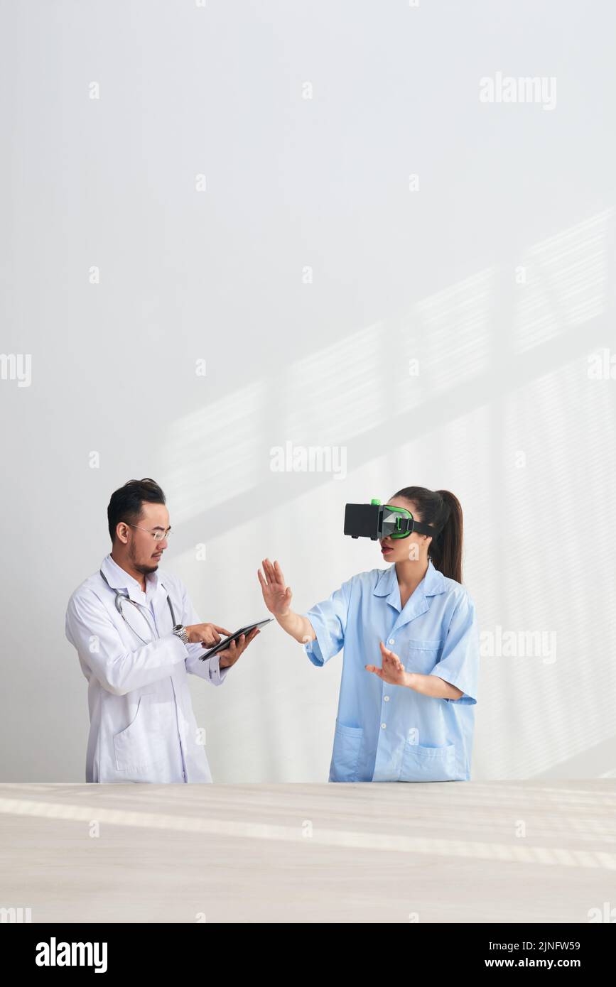 Doctor and nurse with headset and digital tablet testing VR simulator application Stock Photo
